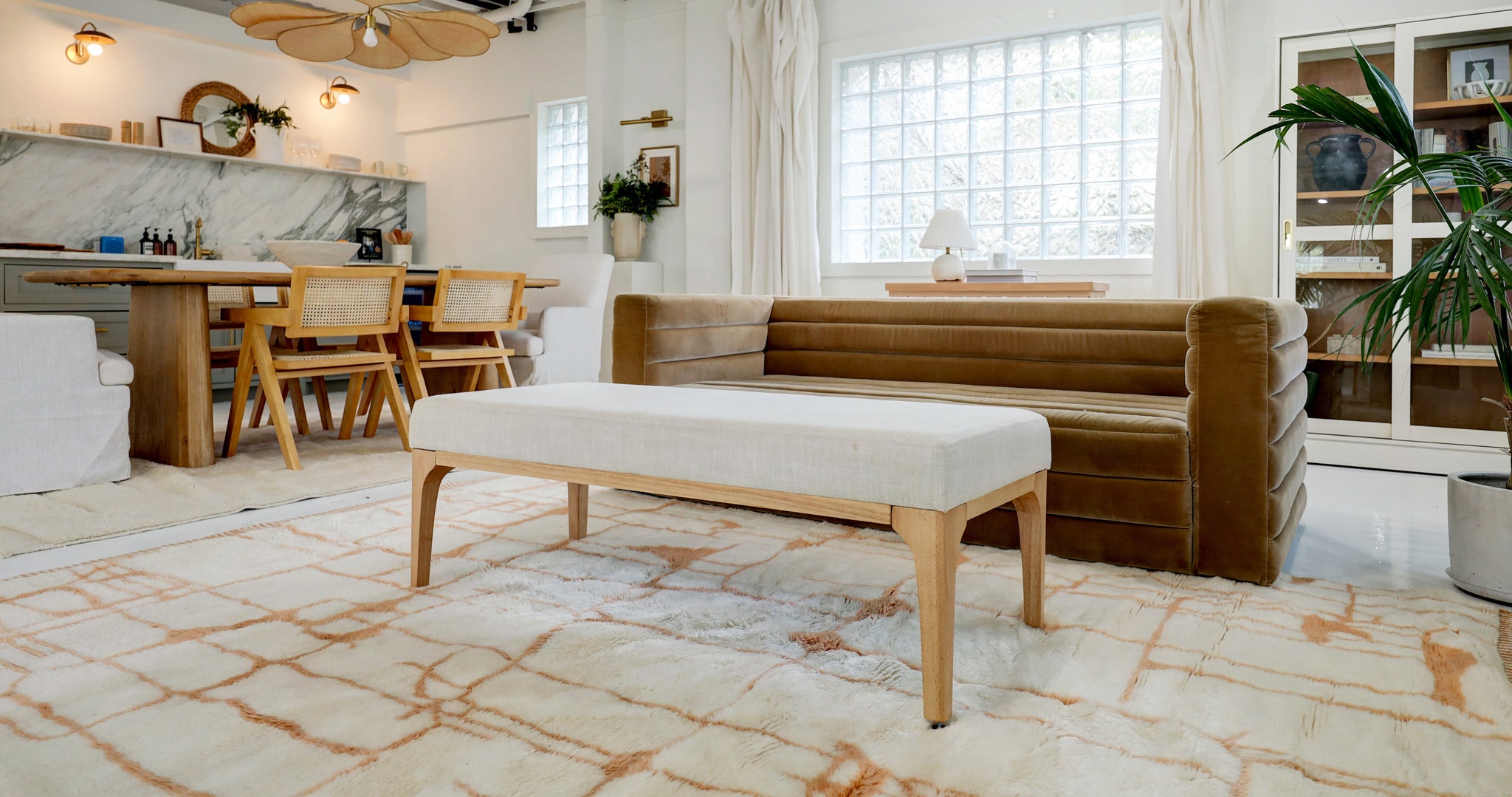 This is a beautifully staged room that shows a bohemian style interior with a soft, plush Moroccan rug with custom Berber designs.  The luxury rug is sitting underneath a mid-century modern style couch. 